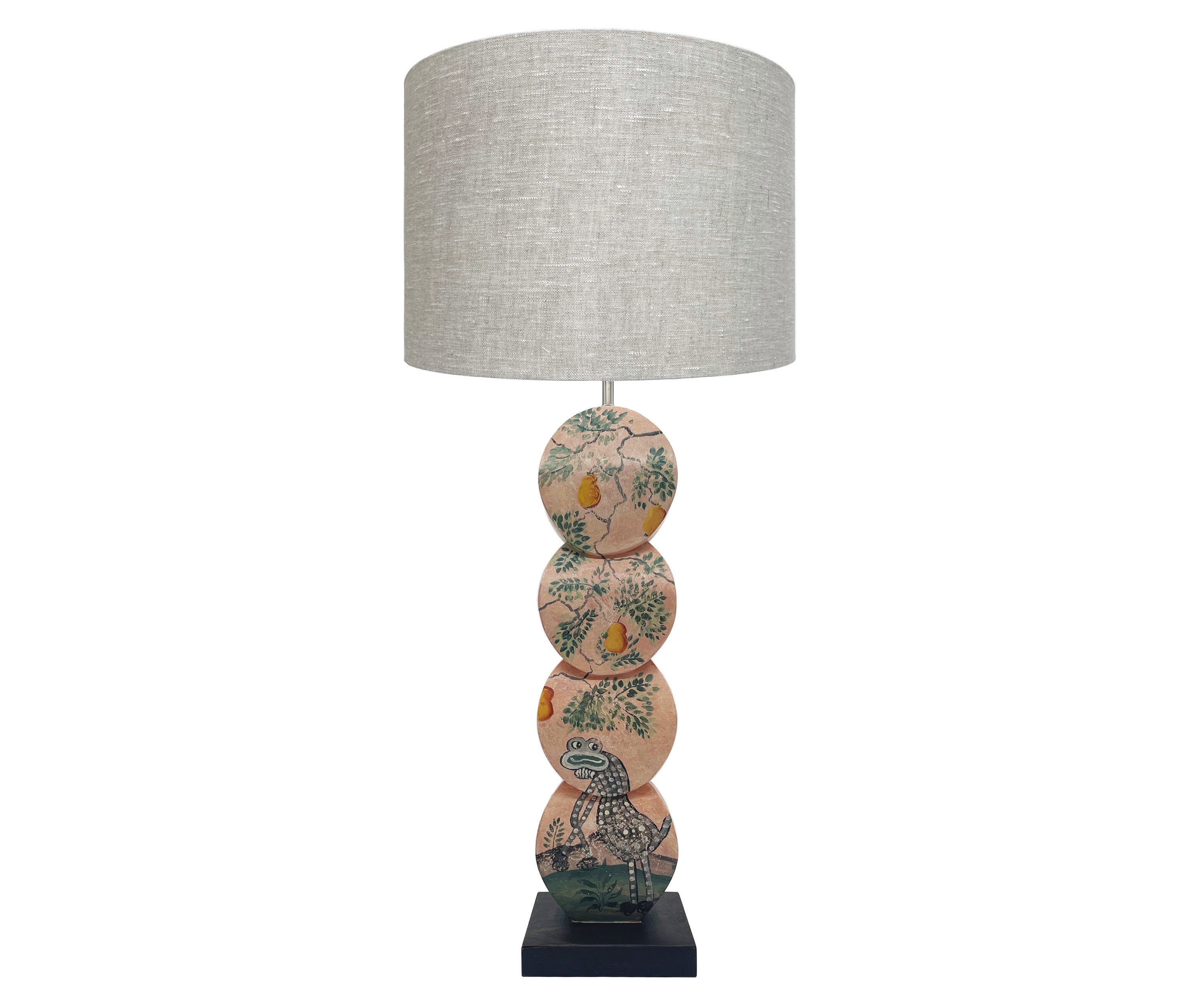 Using Kit's Mythical creatures wallpaper design as inspirations the Mythical Gherkin Disc Lamp, is hand painted by Melissa White, and features the mythical landscape, full of fruit laden trees. The Gherkin, is a frog faced sage coloured creature, which basks under a golden pear tree, against a plaster pink background. This lamp is shown is a plain natural linen cylinder shade.