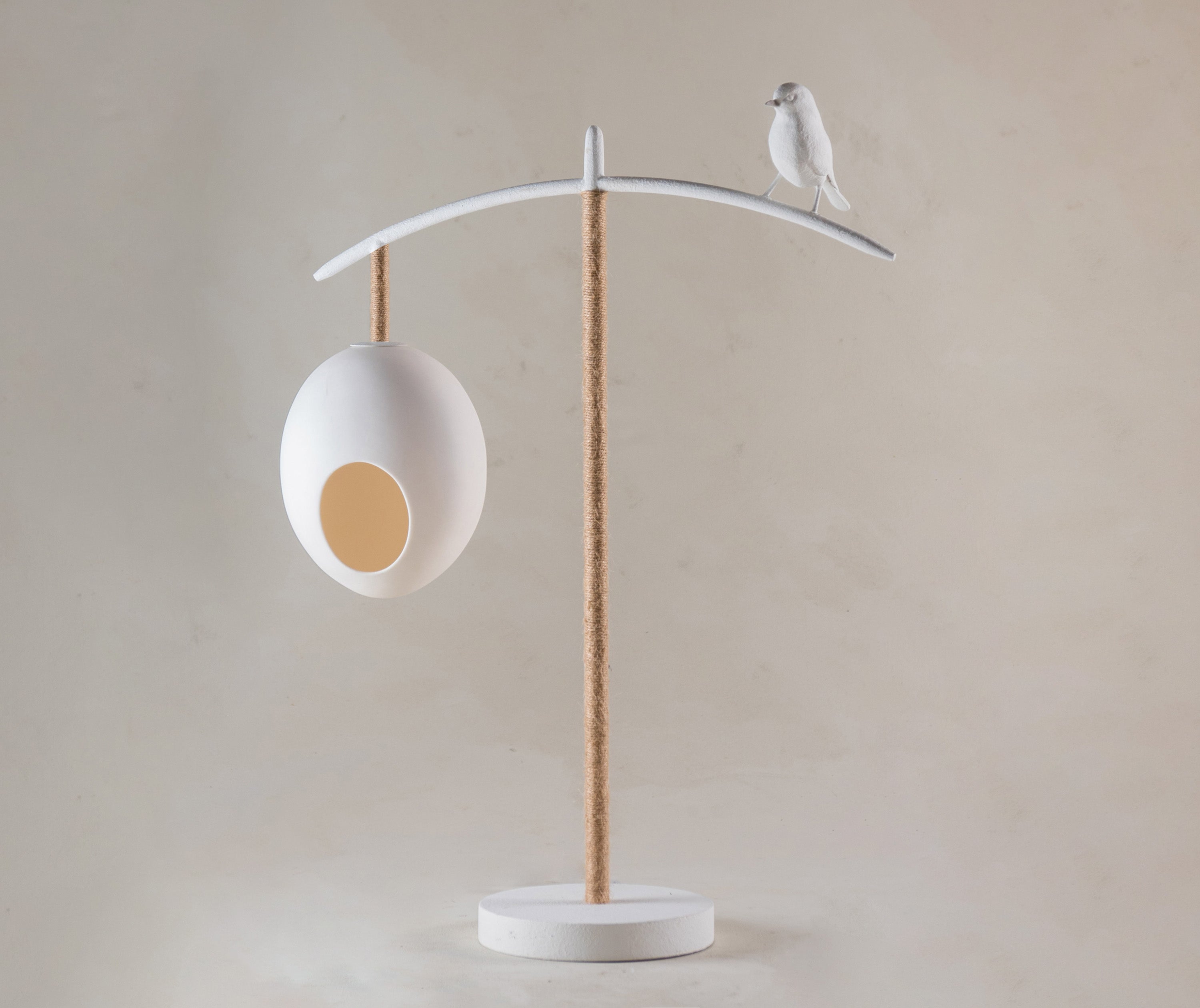 The Sleepy Robin table lamp, stands 55.5mm high, and features two suspended eggs, counter balanced on a branch like frame, softened with organic twine, with a beautifully crafted Sleepy Robin standing proudly on his branch, softened with organic twine, in white.