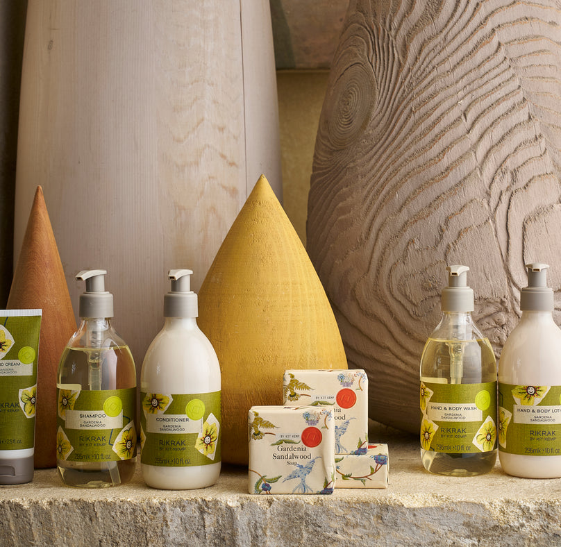 Three body wash bottles lines up next to each other on a marble bathroom counter with green floral labels