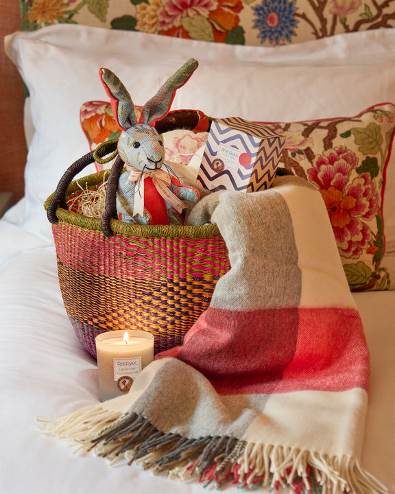 Snug in a Bunny Basket with Kit Kemp favourite patchwork animal bunny toy, 100% merino wool blanket, Lavender and Eucalyptus candle, presented in a colourful woven basket.