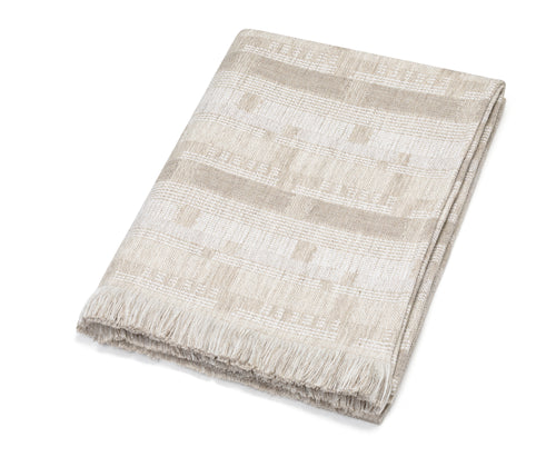 Kit Kemp for Christopher Farr collection. A folded Loom Weave throw. Lines and dashes stripe the fabric in white and shades of neutral on neutral. Showing frayed edges.