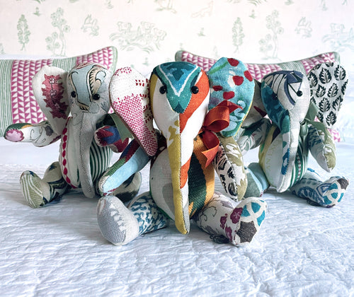 Jambo the elephant patchwork toy, is pictured in a combination of printed and embroidered fabrics all on a natural base, with highlights of pink, blues and duck egg greens, to make a truly unique cuddly toy.