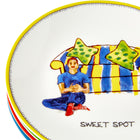 Close up of the yellow Tid-bit dessert plates, showing doodle of man leaning relaxing against his blue and yellow wide striped sofa, on top of a stack of the other plates in the set.