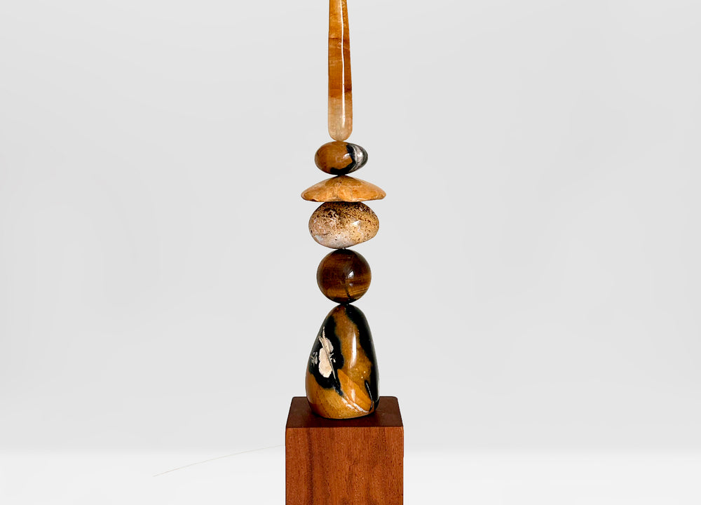 Ancient Sands I is entirely unique and made from an assortment of precious crystal stones. It includes, from the top: A translucent rod of Golden Healer, Yellow Jasper galet, a fossilised Sand Dollar, Pietersite, a Tiger’s Eye sphere and a large free form Yellow Jasper. All sitting on an Iroko wood plinth.