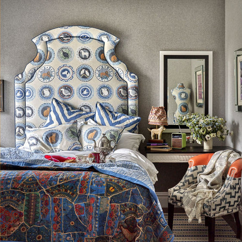 Dorset hotel bedroom with Ellie headboard, featuring Arrow and Robina's Dinner Party cushions in blue and white tones. Foreground shows a Brick pattern throw and reflection of Kit Kemp mannequin in matching Robina's Dinner Party fabric.