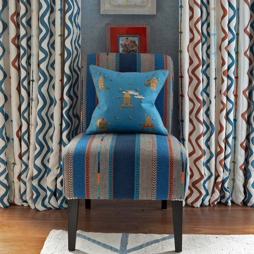 Buzz Off cushion in blue offsets the Bunty upholstered chair and rick rack fabric curtains, part of the interior design scheme by Kit Kemp