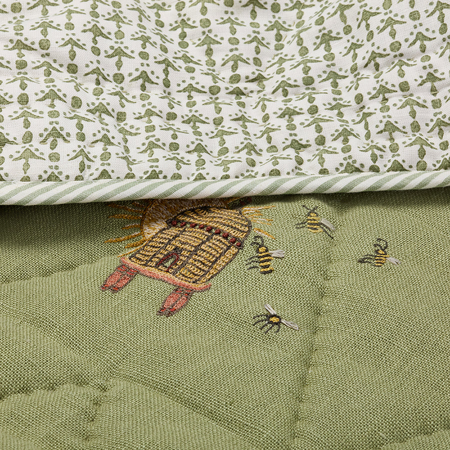 Close-up of the Buzz Off Quilted Bedspread in Green, showcasing intricate embroidered bee and floral motifs on quilted linen with exceptional craftsmanship by Kit Kemp for Chelsea Textiles.