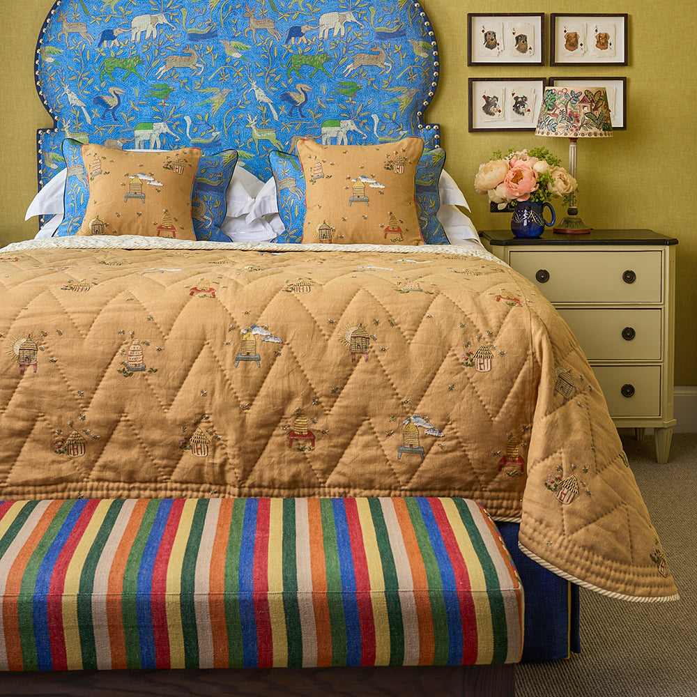 Buzz Off Quilted Bedspread in Yellow styled in with Noah's Ark headboard in Onion shape, showcasing its quilted linen, embroidered bee motifs and playful design by Kit Kemp.