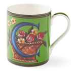 A bold green Mug with a blue C sitting among a basket overflowing with yellow and red flowers, this image appears on both sides of the mug.