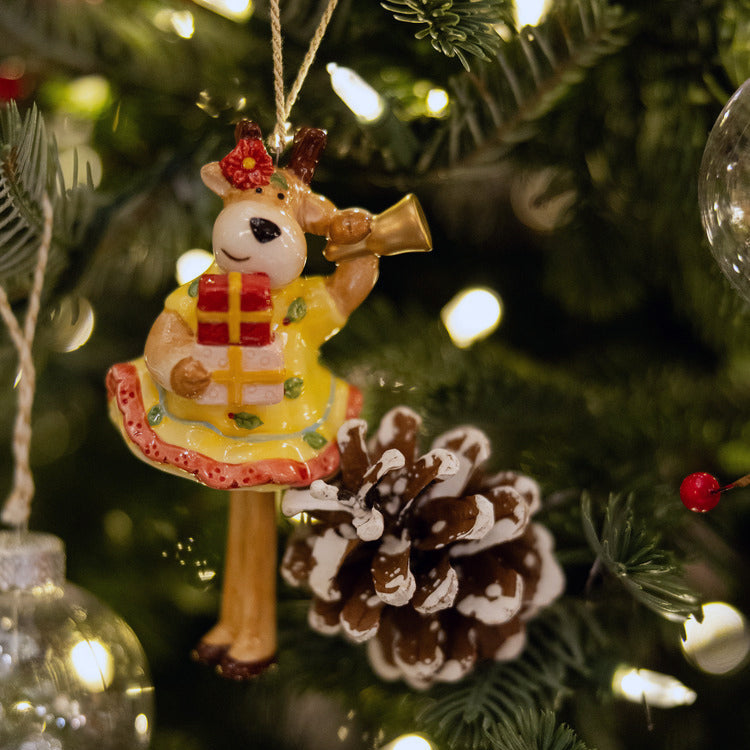 Unique fine china Christmas Bell Reindeer Ornament—a high-quality collectible featuring a cheerful reindeer in a stylish, hand-painted yellow dress. This decoration is full of festive details, including a gold bell, a red present, and playfully articulated, dangling legs, making it a charming statement piece for the holidays.