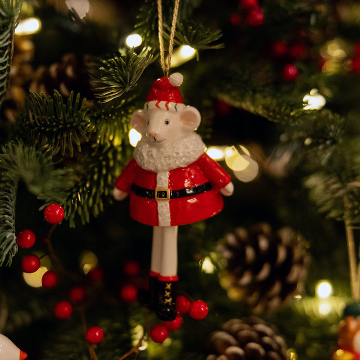 A whimsical Santa Mouse fine china Ornament from the renowned Kit Kemp for Spode Christmas collection. The mouse wears a vivid red Santa suit with a fuzzy white collar and hat. Its dangling, articulated legs give it a fun, dynamic quality. This highly detailed ornament is a stylish and unique piece that will delight collectors and make a memorable gift.