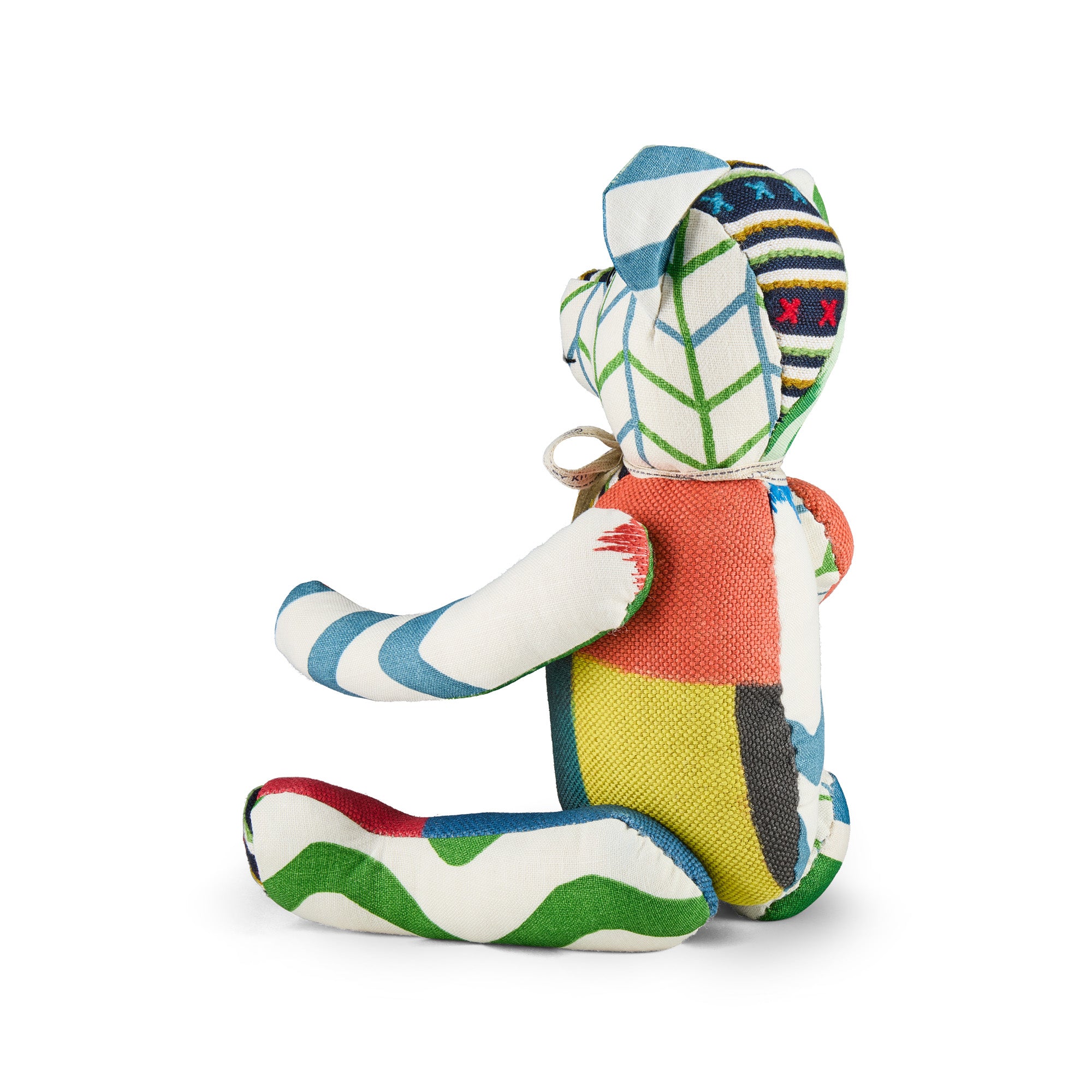 A handcrafted Kit Kemp Willow Bear sitting upright, featuring a torso of horizontal stripes and red cross stitching. The bear is composed of various textured fabric panels in green, turquoise, and orange, finished with a cream-colored ribbon bow around the neck and a '1/4' edition number hand-marked on its right foot.