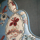 Close up detail of 'Flora' headboard, reminiscent of a Victorian jelly mould, with its graduated triple arches, stands tall and proud. Upholstered in Kit Kemp's Blue 'Chainstitch' fabric, a grand scale floral design, in baby blue with pink and red flowers. 