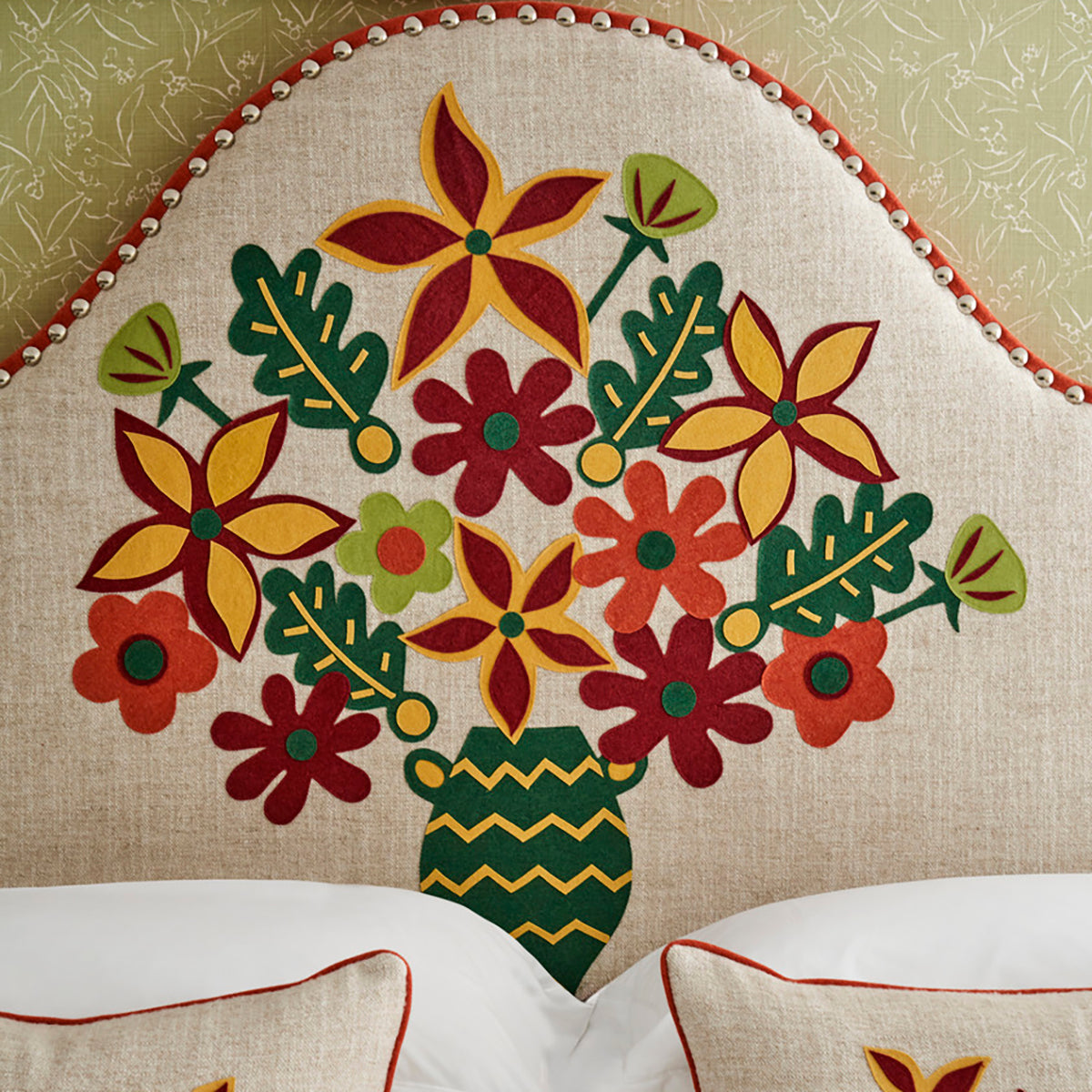 Applique details and handmade details elevate the headboard design with an intricate flowers in a vase motif, with joyful mix of green, yellow, red and orange details.