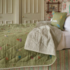 Quilted bedspread with green Garden Shed design fabric featuring bees, ducks, amongst garden tools, vegetables and plant pots, part of the Kit Kemp Weekend Collection.