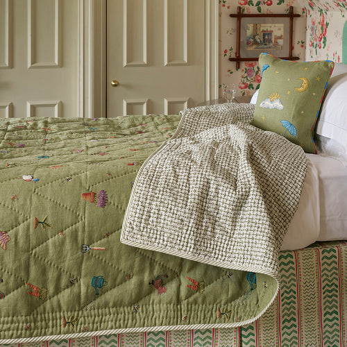 Quilted bedspread with green Garden Shed design fabric featuring bees, ducks, amongst garden tools, vegetables and plant pots, part of the Kit Kemp Weekend Collection.
