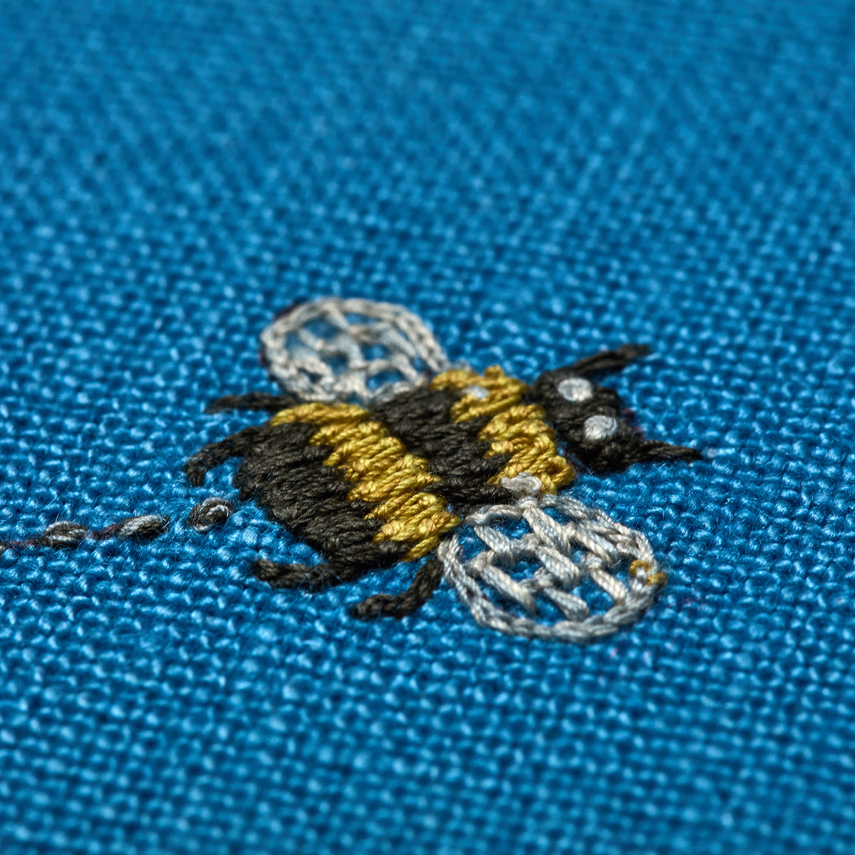 Bee embroidery detail on Garden Shed blue cushion, inspired by the weekend theme by Kit Kemp.