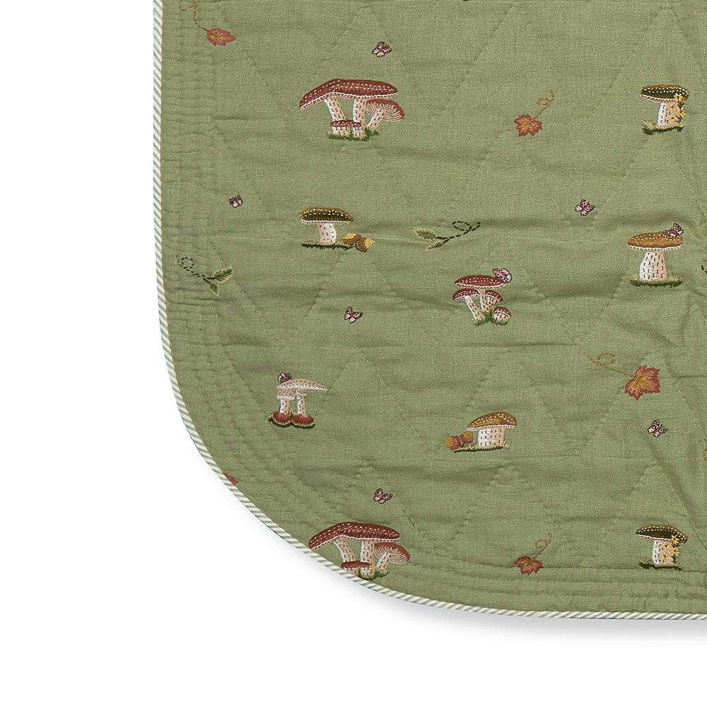 The Good Trip Quilted Bedspread in Green, revealing the elegant quilted linen construction, embroidered woodland pattern and softly rounded corners by Kit Kemp.