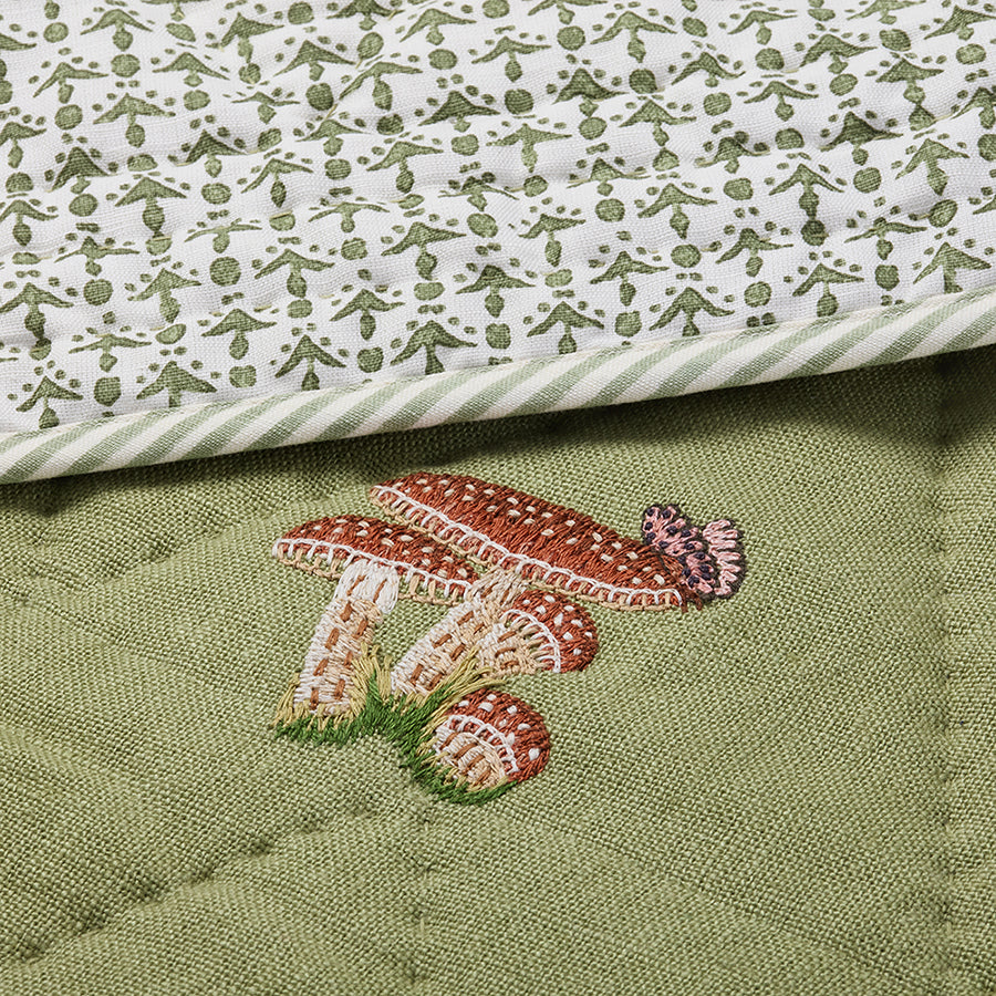 Close-up of the Good Trip Quilted Bedspread in Green, showcasing intricate embroidered mushroom and woodland motifs on quilted linen with beautifully crafted detailing by Kit Kemp for Chelsea Textiles.