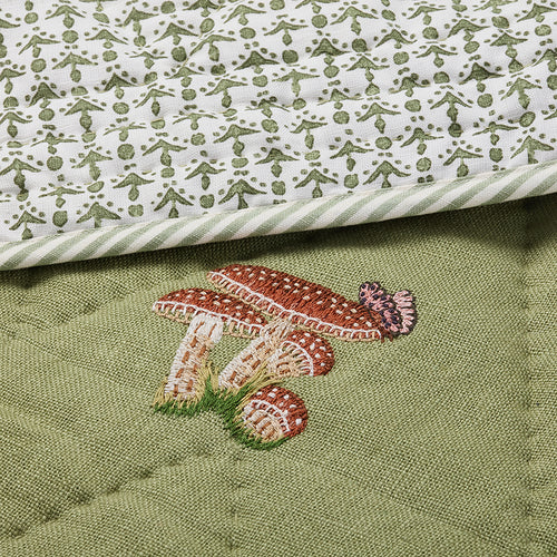 Close-up of the Good Trip Quilted Bedspread in Green, showcasing intricate embroidered mushroom and woodland motifs on quilted linen with beautifully crafted detailing by Kit Kemp for Chelsea Textiles.