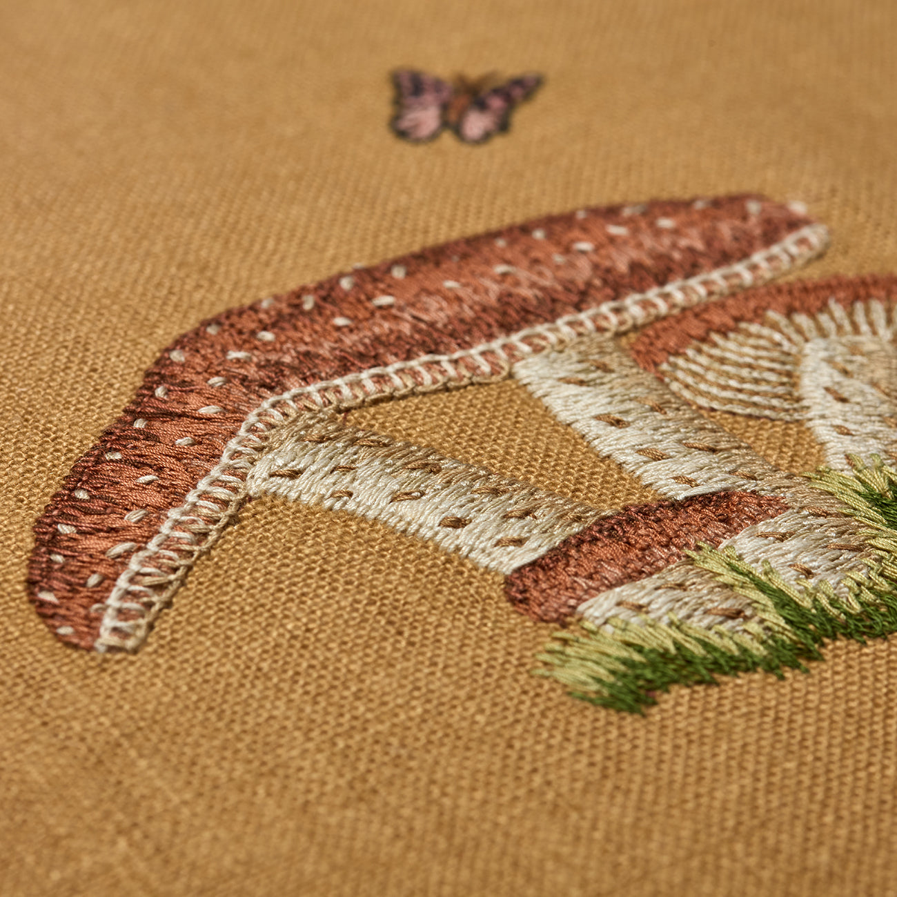 Close up of Good Trip yellow cushion with hand embroidered mushroom detail. Exclusively at Shop Kit Kemp.