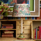 A wooden fluted lampbase and decorative handpainted shade sitting on a desk