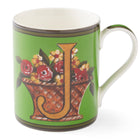 The gold J on this emerald green mug sits among a basket overflowing with yellow and red flowers.