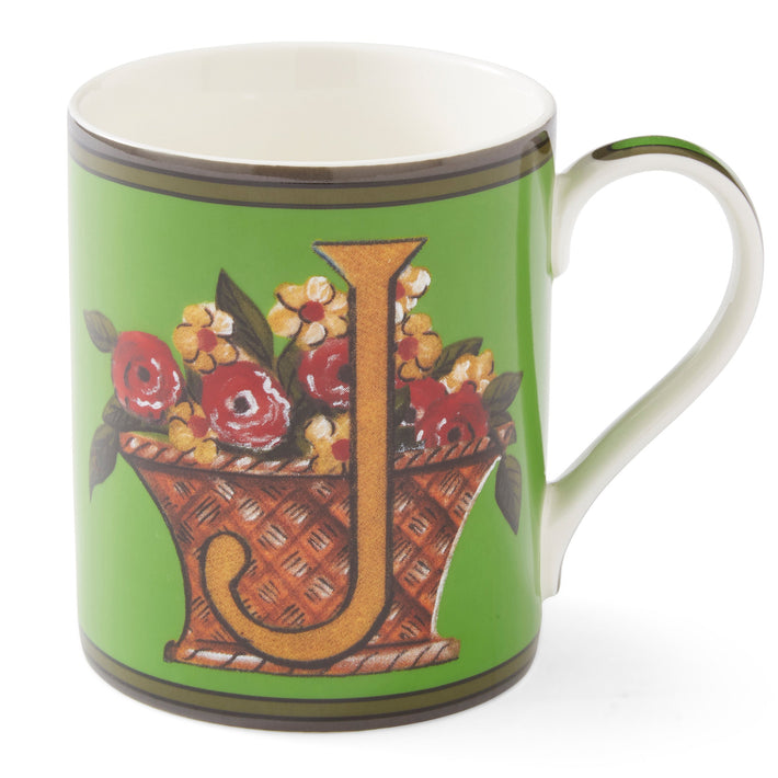 The gold J on this emerald green mug sits among a basket overflowing with yellow and red flowers.