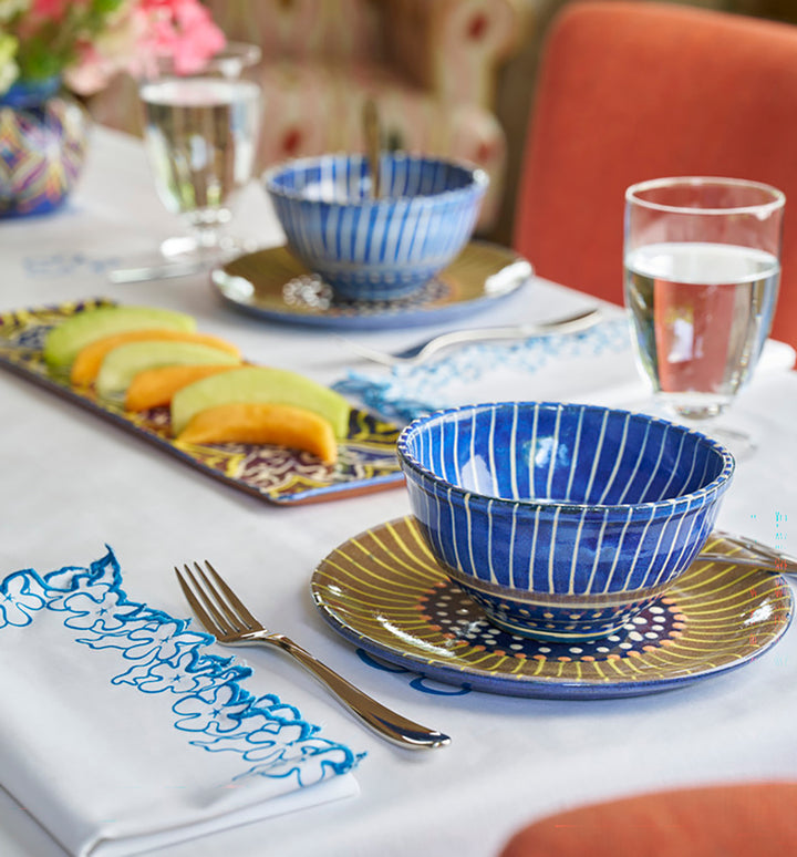 Dining table setting with blue and gold ceramic bowls and plates. inspired by Barbados' sea urchins and the island's marine ecosystem. 
