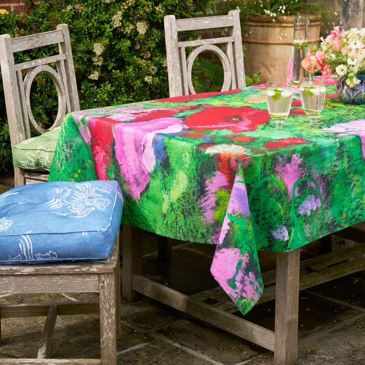 Bright colour outdoor and indoor tablecloth with hand-painted floral design, paired with Friendly Folk outdoor picnic cushions. Exclusively at Shop Kit Kemp.