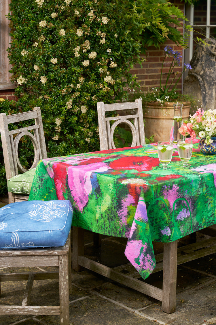 Bright colour floral tablecloth on a wooden table, surrounded by chairs and outdoor seating 