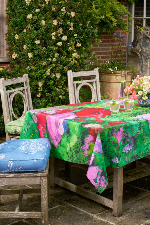 Bright colour floral tablecloth on a wooden table, surrounded by chairs and outdoor seating 