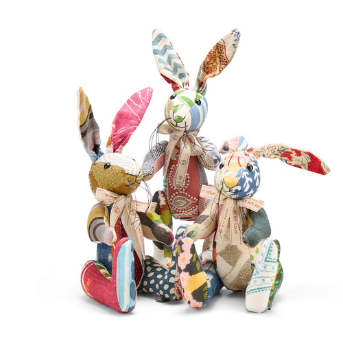 A charming group of three handmade Minnie Rabbits from Kit Kemp’s Patchwork Collection, showcasing a vibrant mix of premium designer fabrics. The rabbits feature an eclectic blend of patterns, including bold pink stripes, delicate polka dots, and botanical tapestries, all tied together with signature cream ribbons.