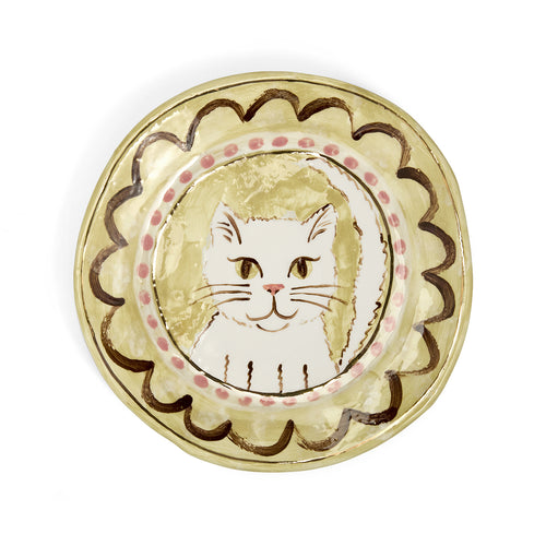 A hand-painted decorative ceramic plate by Sasha Compton titled "My Buttercup Kitten," featuring a central illustration of a seated tabby cat in soft yellow tones, encircled by a pink-dotted border and wide, expressive brushstrokes in deep clay-brown.