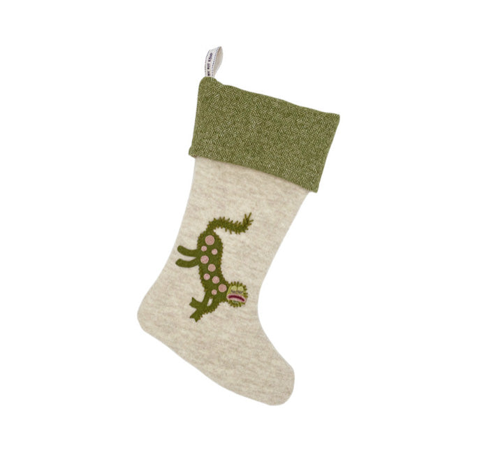 A whimsical green Christmas stocking with a mythical gherkin creature appliqué on one side and a pear appliqué on the other,