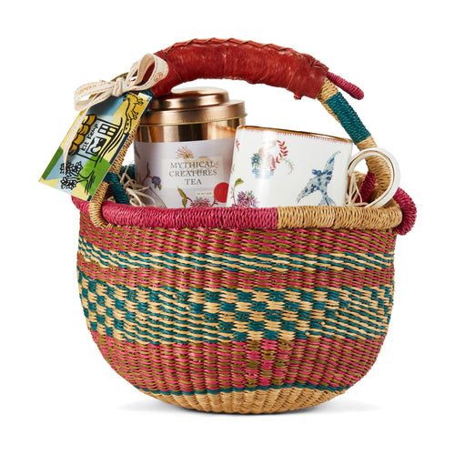 Mythical Creatures Tea set is presented in a colourful woven basket with a leather handle, containing a tin of Mythical Creatures tea caddy tin, and a ceramic mug with a Mythical Creatures design. 