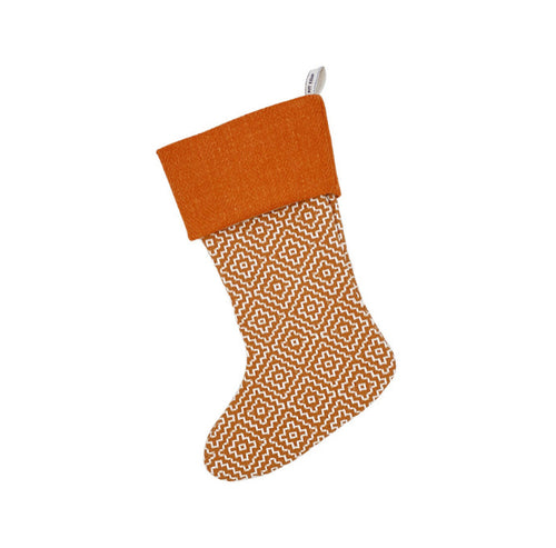 Shop Kit Kemp orange geometric patterned Christmas stocking with a plush orange top and a decorative pattern extending down the leg, to bring a joyful pop of colour to any mantelpiece. 