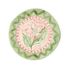 Hand-painted "Pink Hellebores in the Garden" ceramic plate by Sasha Compton for Shop Kit Kemp, featuring a central pink floral motif encircled by a dusty rose dotted rim and a wide green geometric zigzag pattern. 