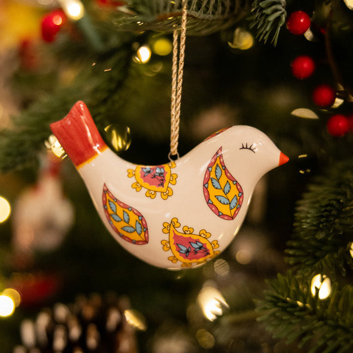 The elegant Puffed Bird Floral Paisley fine china Ornament from the Kit Kemp for Spode collection. This unique bird-shaped decoration has a white body adorned with vibrant, stylized yellow, pink, and blue paisley floral patterns and a striking red tail. A designer, high-quality piece that offers a beautiful pop of colour and unique artistry to your Christmas tree.