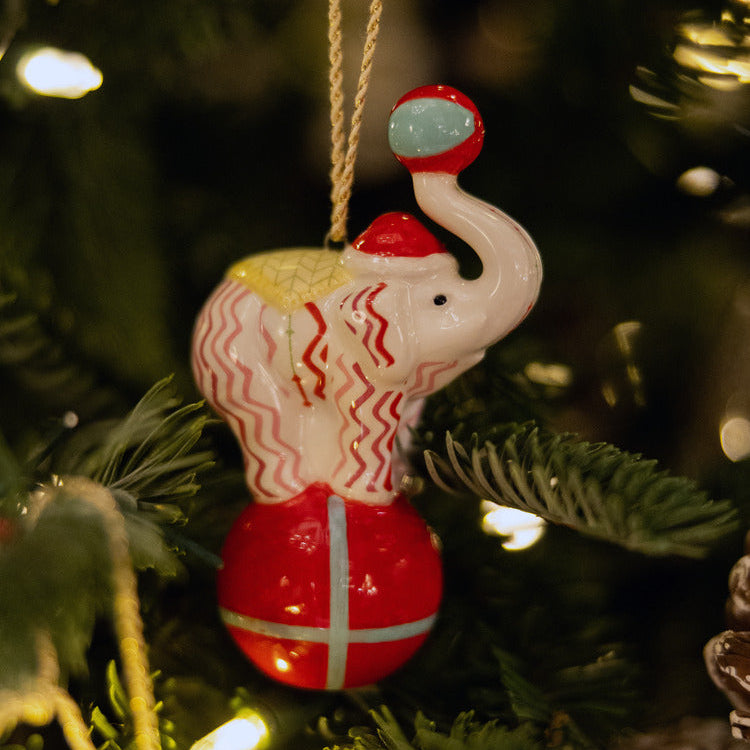 Kit Kemp for Spode fine china Rik Rak Elephant Ornament. This charming decoration features a circus elephant balancing on a red ball, decorated with the signature Rick Rack zigzag pattern. A unique and high-quality piece that is perfect for collectors and anyone seeking a whimsical, artistic touch for their Christmas tree.