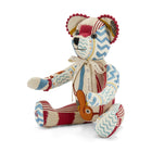 A luxury patchwork bear featuring unique ruby-red beading around the ears and hand joints. Crafted from a sophisticated mix of neutral linens, crimson Lost and Found limbs, and blue and yellow Wriggle Room patterns, this Firmdale Ruby Anniversary bear showcases artistry and tactile detail.