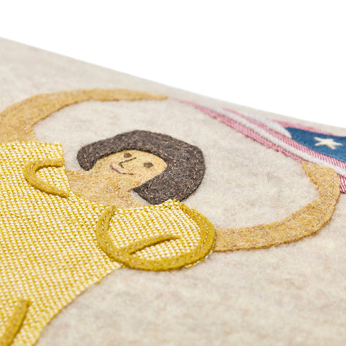 Close-up of the artisan-made appliqué, showing the lady in a yellow dress waving American flag, hand-stitched on soft 100% Chamonix wool.