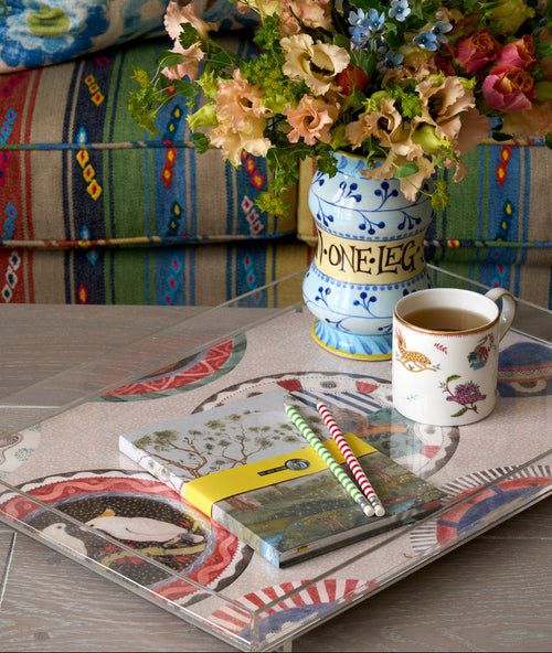 Katrin Moye vase artwork paired with Mythical Creatures tea mug, Lantern Parade notebook and pencils and Robina's Dinner Party Acrylic tray, on Kit Kemp coffee table, for a versatile lifestyle decor.
