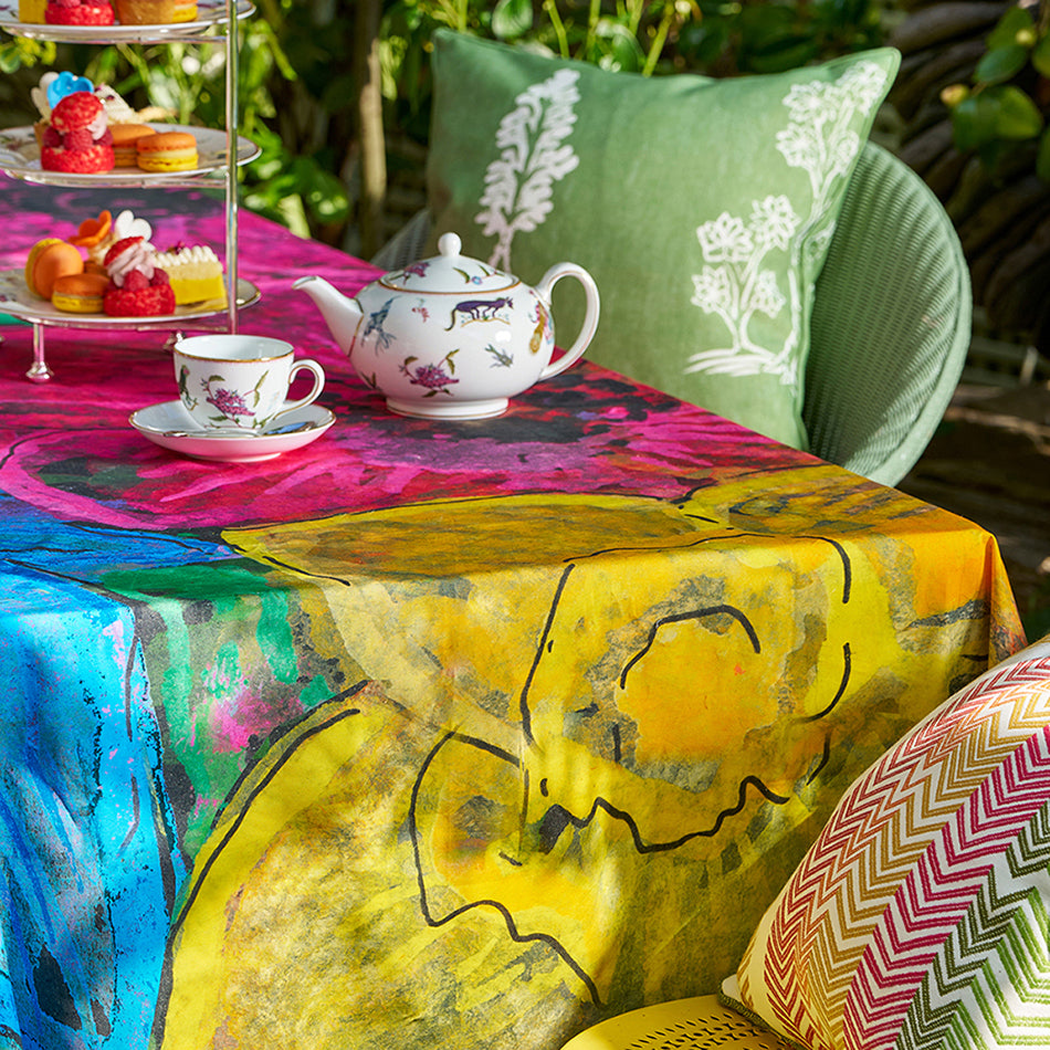 Kit Kemp tea-ware and glassware on the Sunshine tablecloth, showing the saturated colours of the Indian-made cotton and its practical, water-resistant finish.