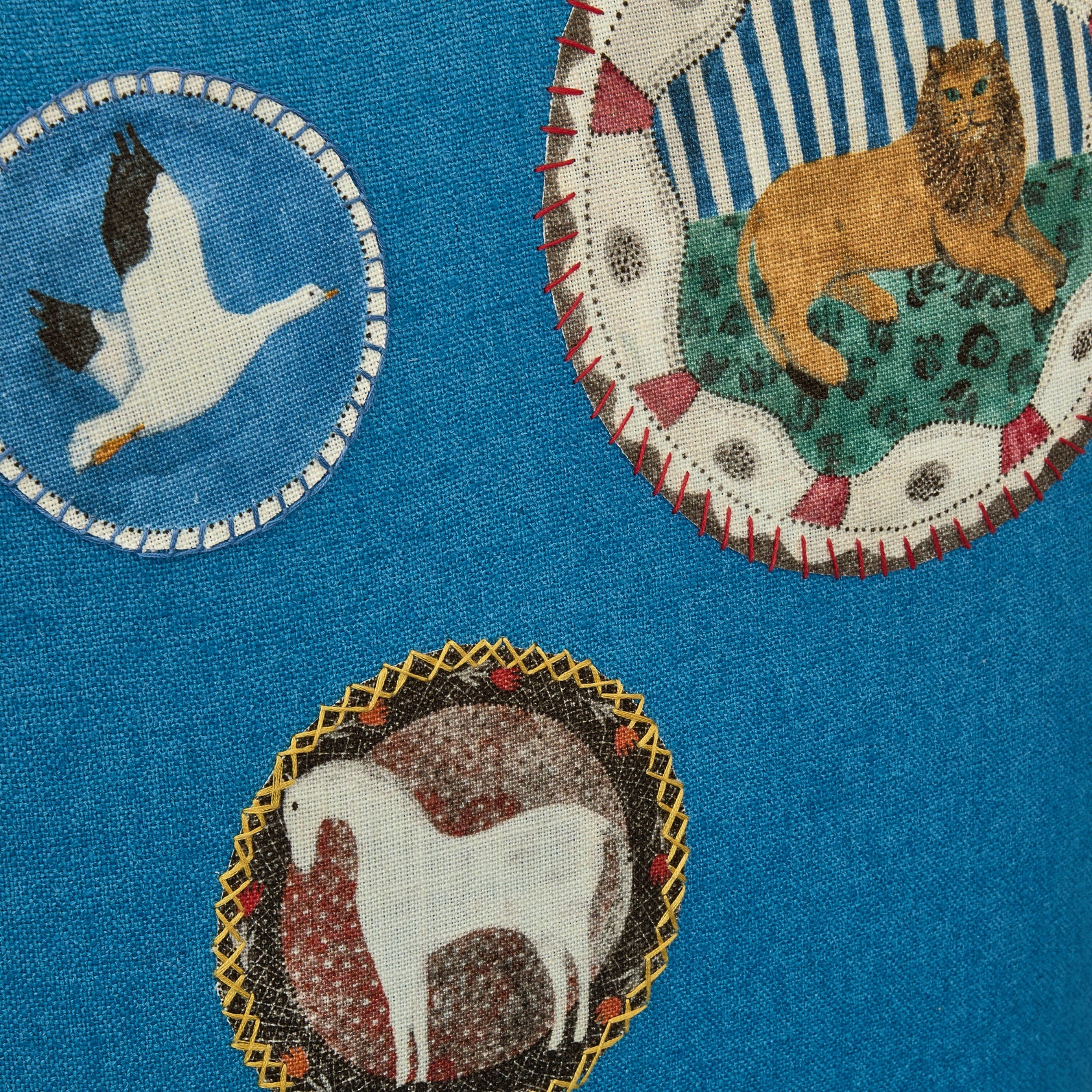 Embroidered patches of a goose, lion, and horse on a blue fabric background.