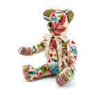 Handmade Sycamore Willow Bear in Pierre Frey Fronsac fabric, a high-end textile known for its colourful, decorative embroidery. This exclusive character features a signature "By Kit Kemp" cream ribbon and a unique "2/2" numbered edition stamp on its striped foot, highlighting its rarity and artisanal British heritage.