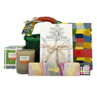 A woven African basket with a leather handle, containing Kit Kemp notebook, A5 notecards, Firmdale pencils box, and a RikRak wheatgrass candle. A perfect present for a writing enthusiast and a self-care gift.