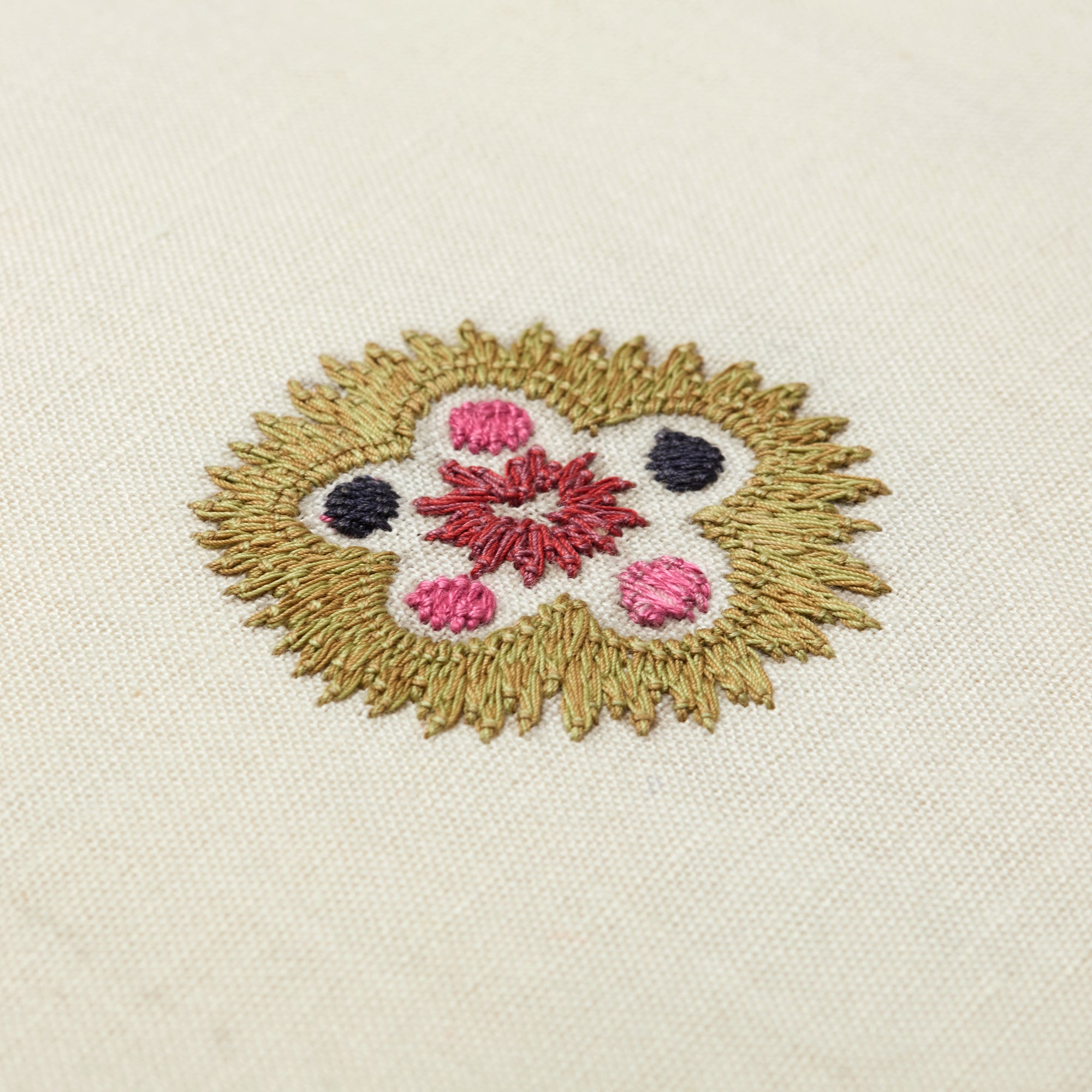 Hand-embroidered Kit Kemp Design Studio cushion featuring intricate Suzani motifs in a palette of pink and mauve on a linen-cotton base. This 41cm (16in) square cushion showcases the collaboration with Chelsea Textiles, complete with a contrasting pink piped edge and unique pattern placement.