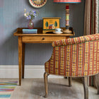 The West Timber Tub Chair embraces you in its curved arms and boasts a rollover top and elegant wooden legs. Upholstered in Kit Kemp's 'Hotline', a vibrant, fun fabric from the collection created in collaboration with Christopher Farr, it takes on a new dynamic energy, with its textured stripe effect, and intricate woven stitch detailing in earthy terracotta tones.