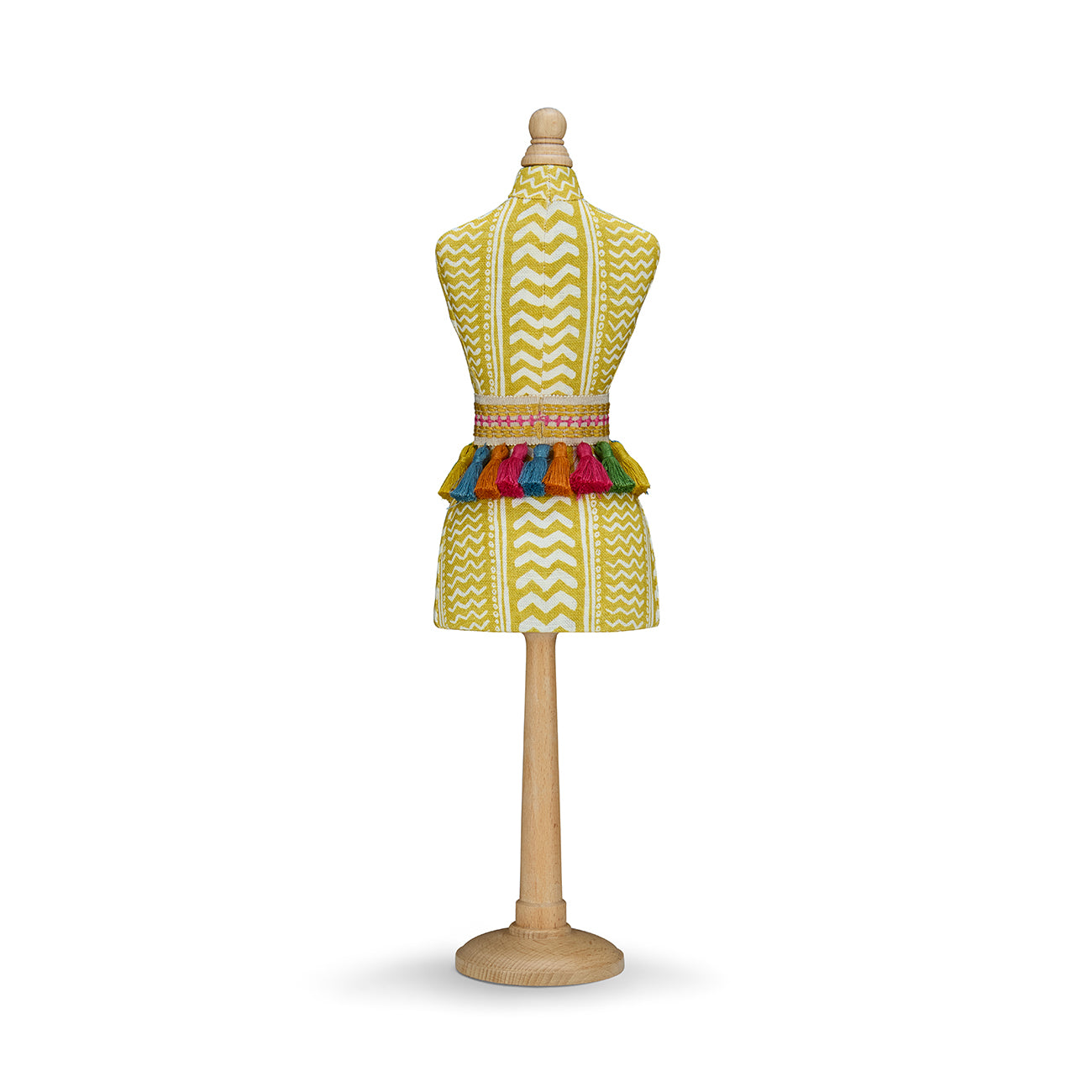 A handmade paper-mâché mini mannequin covered in a textured yellow "Tweak" fabric with a chevron-like weave. It is cinched at the waist with a fun, multicolour tassel belt and stands on a light wood base.